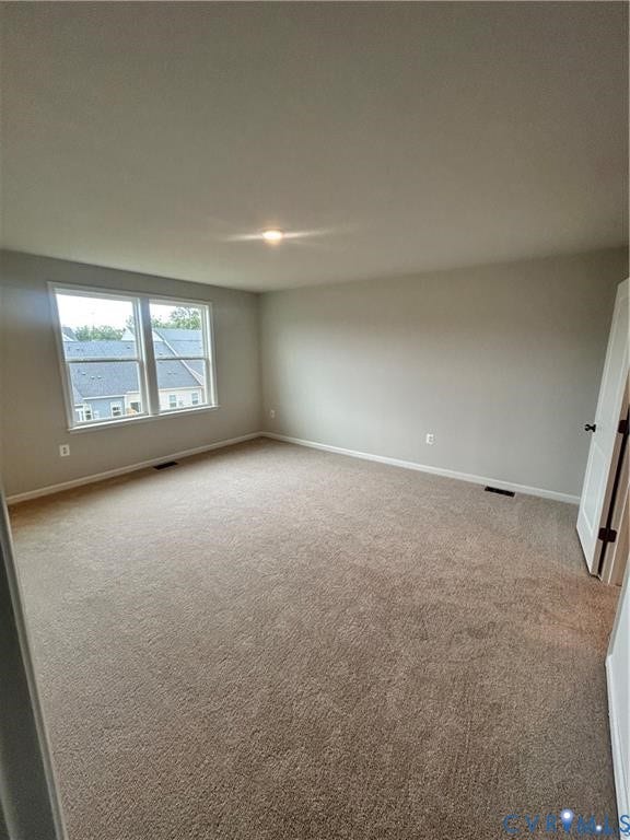 Expansive room with neutral carpeting, light-toned wall paint, and a double window