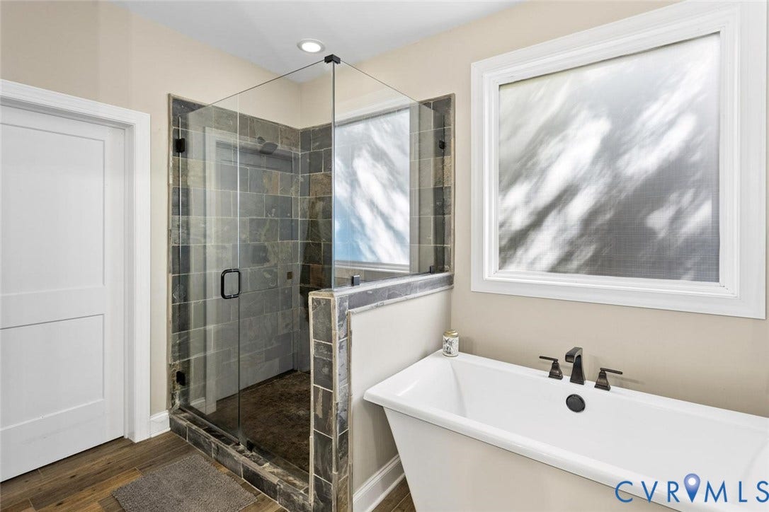 9013 Old Holly Road, Southhampton, Richmond, VA 23235 Glass-enclosed shower with stone tile, freestanding bathtub with matte black fixtures, and wood-finish flooring