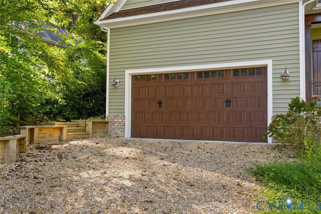 9013 Old Holly Road, Southhampton, Richmond, VA 23235 Wood-finish garage door with upper window panels, light green horizontal siding, and a gravel driveway