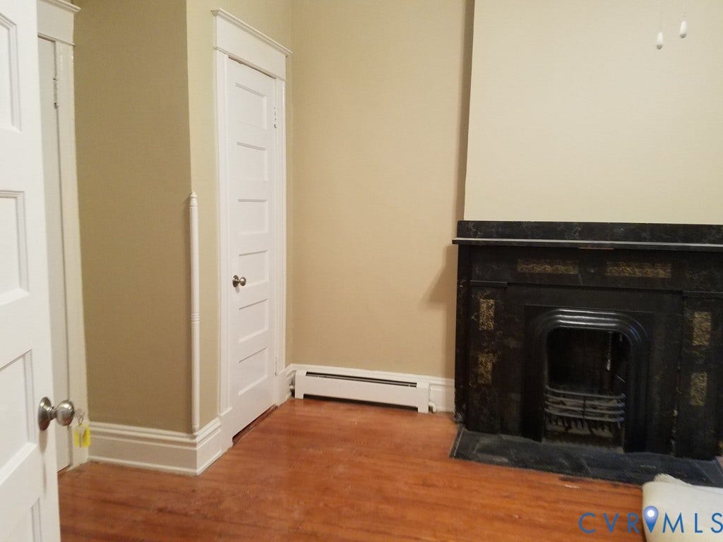 Hardwood flooring, decorative fireplace, white baseboard trim, and paneled interior doors