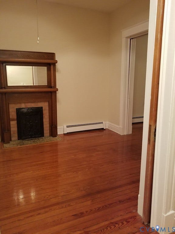 Warm wood flooring, classic wood mantel with integrated mirror, and a tiled fireplace surround
