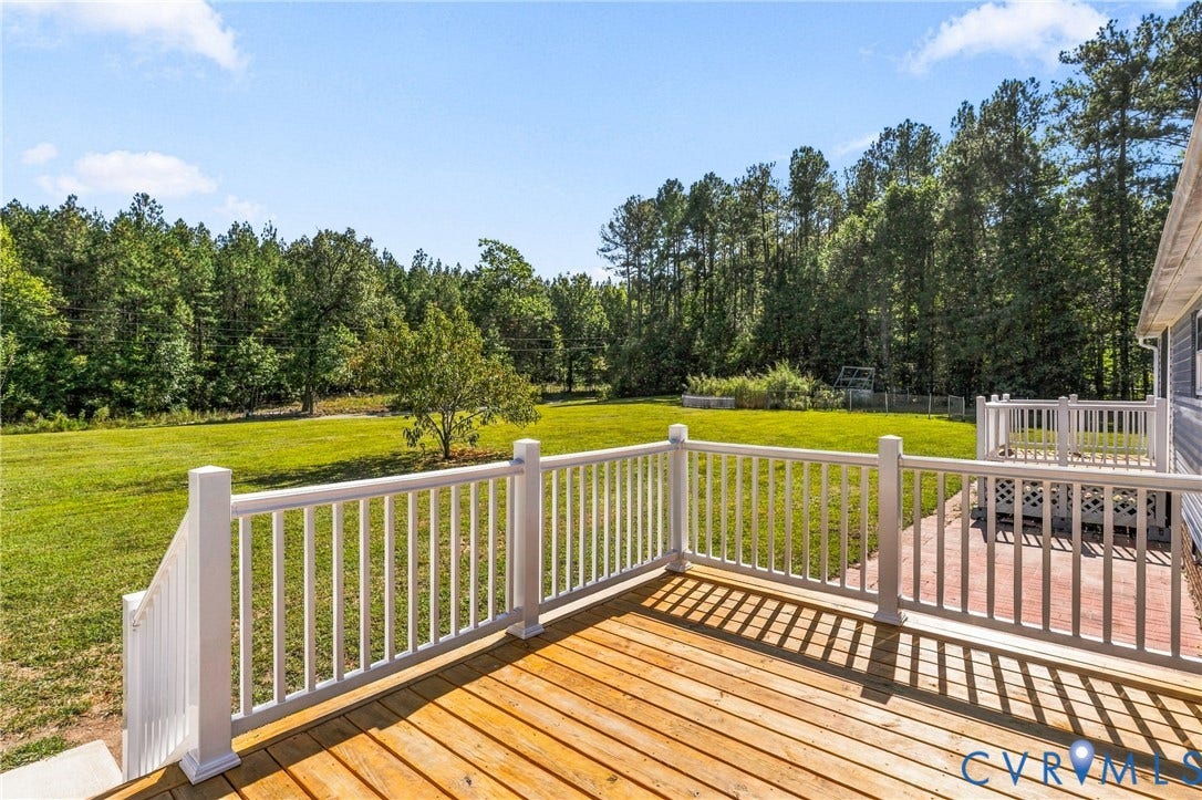 8211 Brills Road, Dinwiddie, VA 23872 Expansive wooden deck with white railings, a lower patio area, and a large grassy yard bordered by mature trees