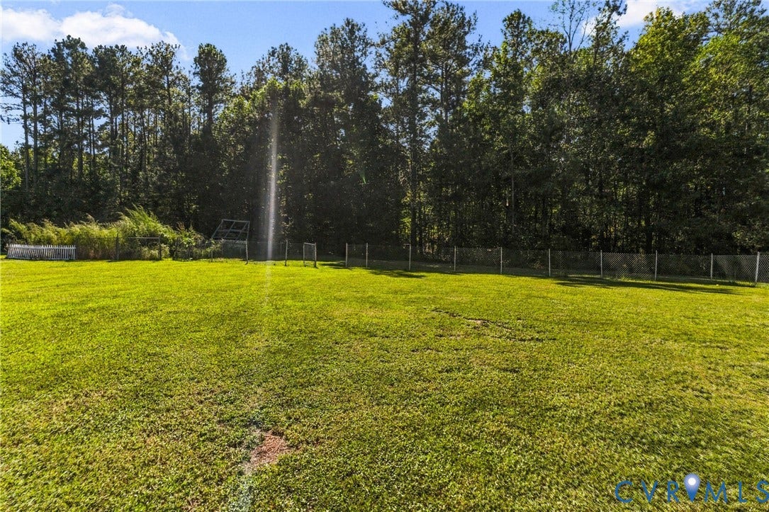 8211 Brills Road, Dinwiddie, VA 23872 Expansive green lawn bordered by a chain-link fence and mature trees