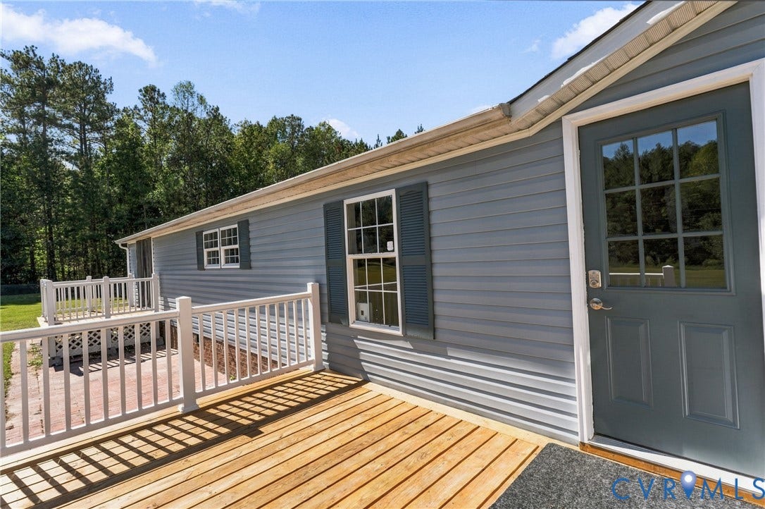 8211 Brills Road, Dinwiddie, VA 23872 Exterior featuring blue horizontal siding, white window trim, operable louvered shutters, and a wood-finish deck with white railings