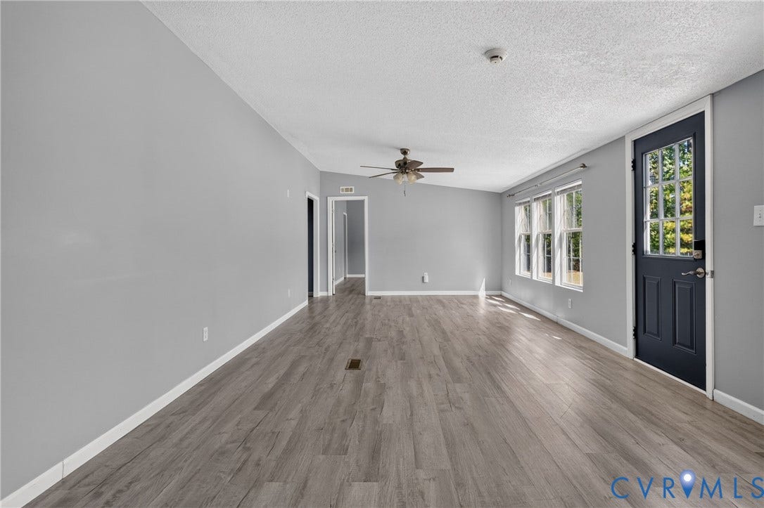 8211 Brills Road, Dinwiddie, VA 23872 Spacious room featuring wood-finish flooring, light gray wall paint, white trim, multiple windows, and a ceiling fan