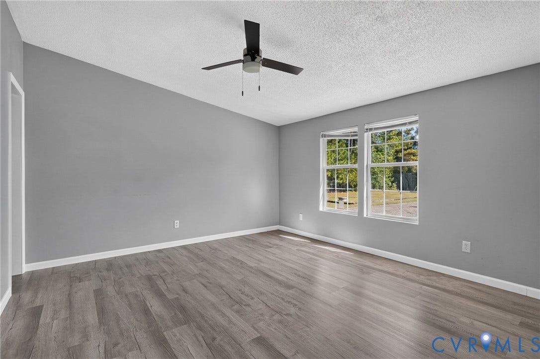 8211 Brills Road, Dinwiddie, VA 23872 Spacious room featuring wood-finish flooring, two window units, and a ceiling fan