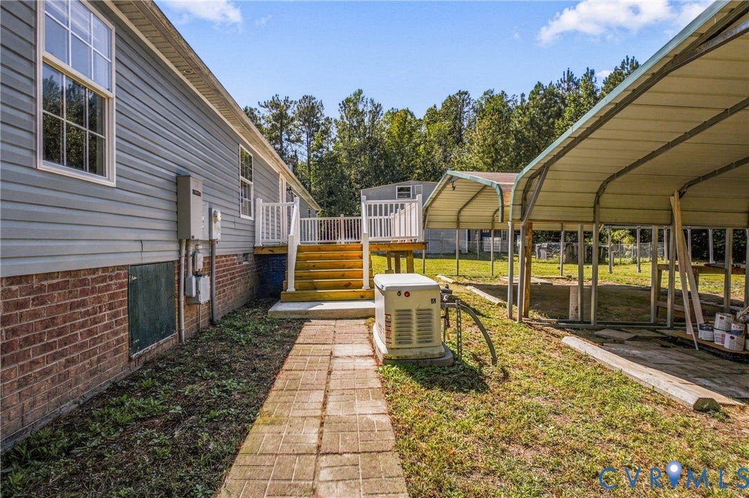 8211 Brills Road, Dinwiddie, VA 23872 Property exterior with light blue siding, brick foundation, and a raised wood-finish deck with white railings and stairs
