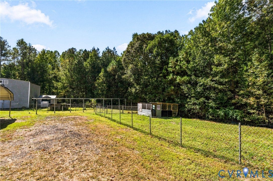 8211 Brills Road, Dinwiddie, VA 23872 Expansive outdoor area with a partially fenced perimeter, lush green space, and mature trees providing a natural backdrop