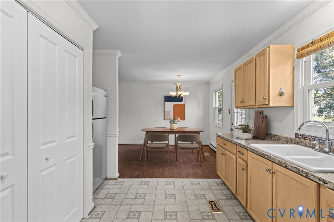 Galley kitchen with wood-finish cabinetry, speckled countertops, and a double basin sink. Photo digiitally staged.