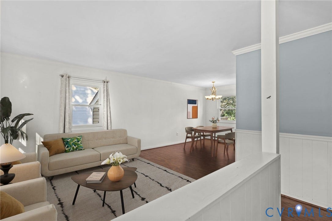 Hardwood-style flooring throughout, white painted walls, crown molding, and a built-in wainscoting detail. Photo virtually staged.
