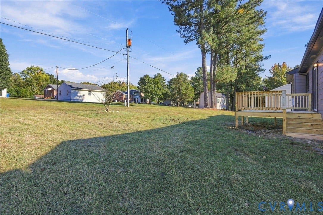5113 Olympic Lane, North Dinwiddie, VA 23803 Expansive backyard with mature trees and lush landscaping, complemented by a composite deck with railings