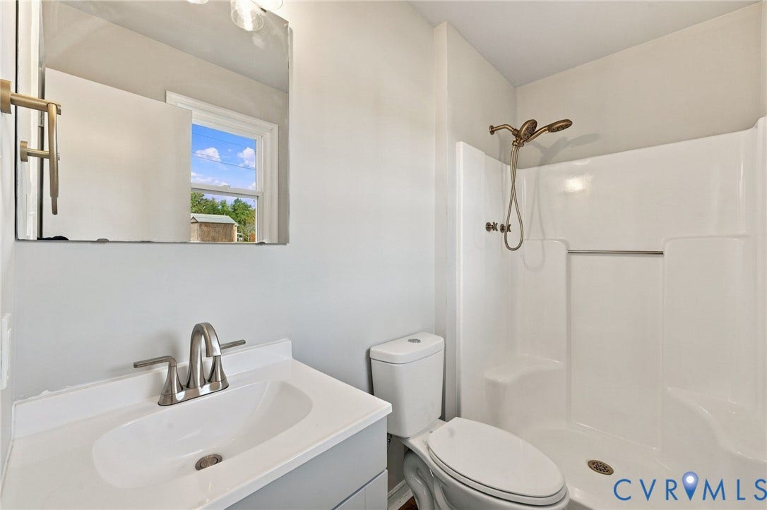 5113 Olympic Lane, North Dinwiddie, VA 23803 Vanity with a white countertop and integrated sink, brushed nickel faucet, large wall mirror, and a shower with a bronze-finish showerhead