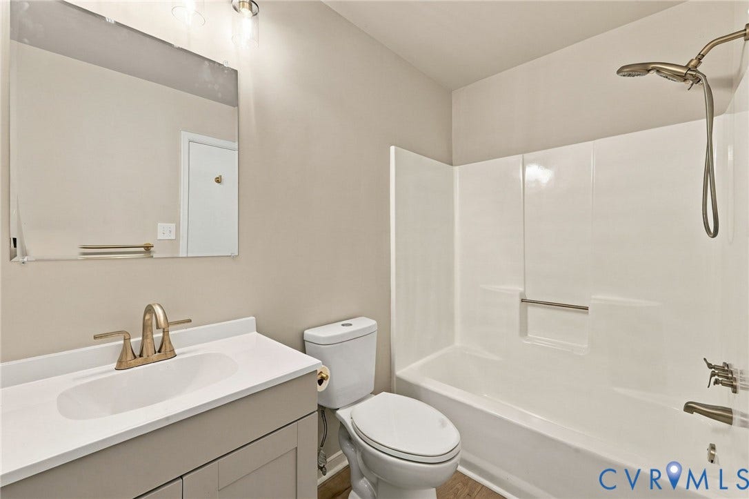5113 Olympic Lane, North Dinwiddie, VA 23803 Modern bathroom featuring a vanity with white countertop and brushed nickel faucet, ceramic vessel sink, and framed mirror