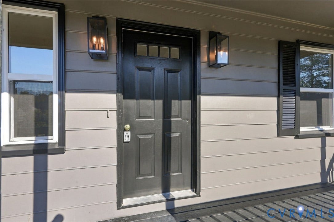 5113 Olympic Lane, North Dinwiddie, VA 23803 Panel siding exterior with a paneled entry door, transom window, and two exterior sconces