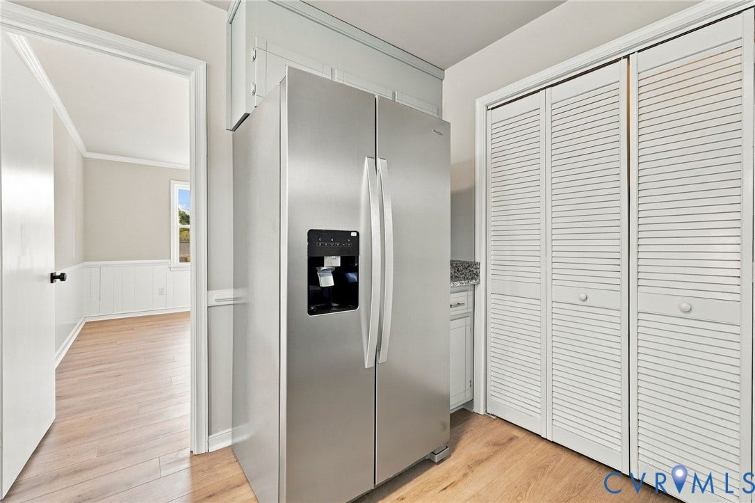 5113 Olympic Lane, North Dinwiddie, VA 23803 Stainless steel side-by-side refrigerator, wood-finish flooring, white louvered bifold closet doors, and a partial view of a window