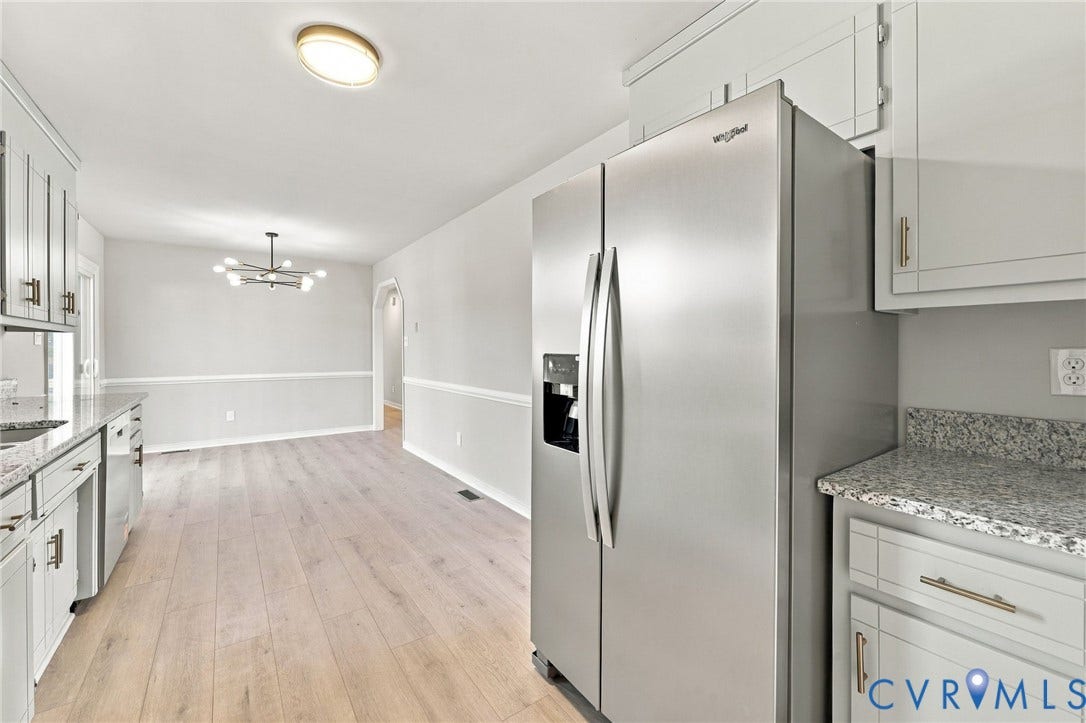 5113 Olympic Lane, North Dinwiddie, VA 23803 Stainless steel French door refrigerator, light wood-finish flooring, white cabinetry with gold-tone hardware, speckled countertops, and an arched doorway