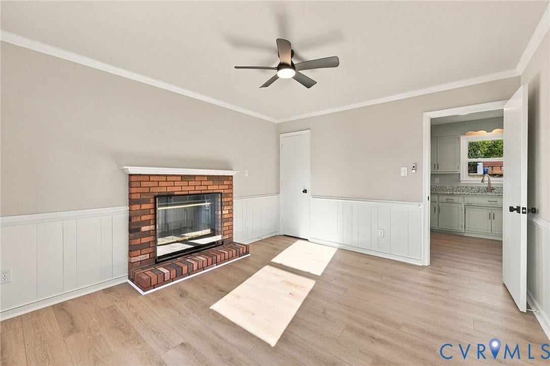 5113 Olympic Lane, North Dinwiddie, VA 23803 Brick fireplace with white mantel, wood-finish flooring, ceiling fan with integrated lighting, and board and batten wainscoting