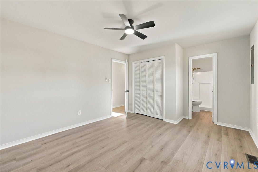 5113 Olympic Lane, North Dinwiddie, VA 23803 Light wood-finish flooring, ceiling fan with matte black blades, white louvered bifold closet doors, and light gray wall paint