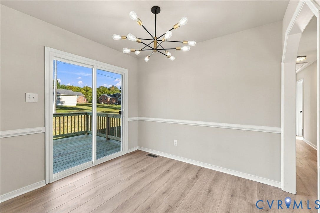 5113 Olympic Lane, North Dinwiddie, VA 23803 Sliding glass doors opening to a wood deck, modern sputnik chandelier, wood-finish flooring, and decorative wall molding