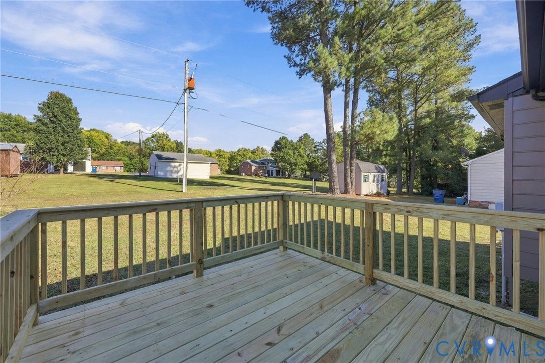 5113 Olympic Lane, North Dinwiddie, VA 23803 Expansive rear deck with natural wood balusters and a large grassy yard featuring mature trees