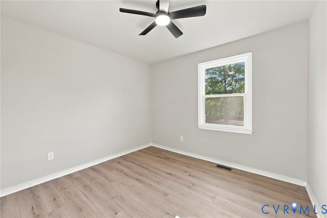 5113 Olympic Lane, North Dinwiddie, VA 23803 Neutral-toned walls, wood-finish flooring, white window trim, and a ceiling fan with light fixture
