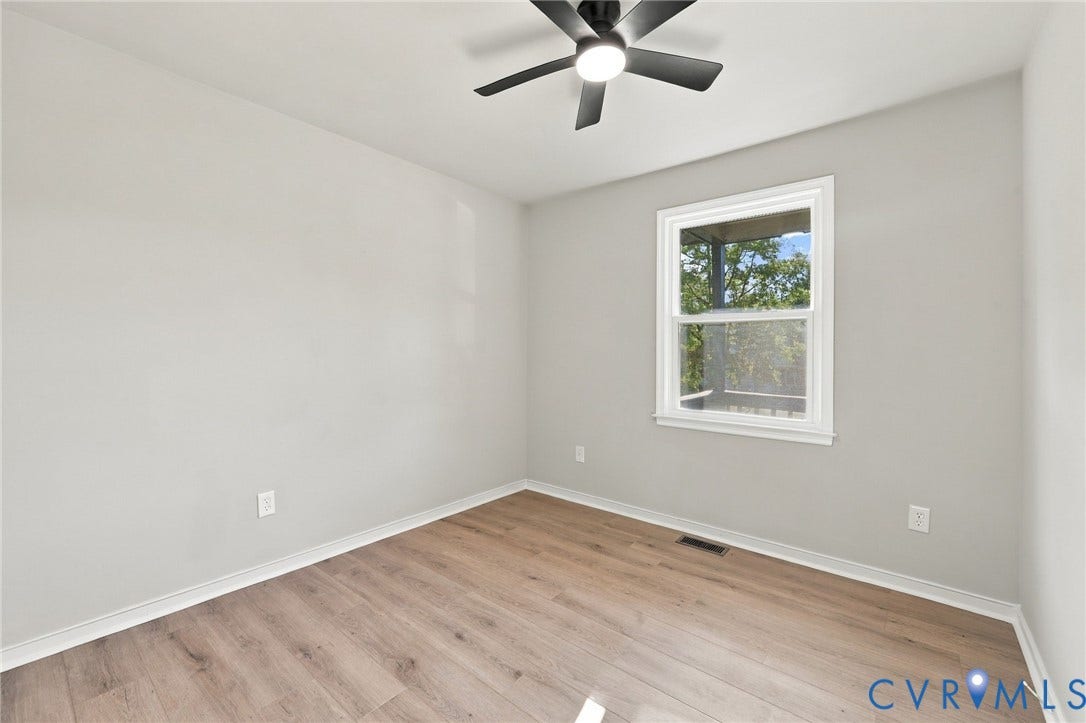 5113 Olympic Lane, North Dinwiddie, VA 23803 Light wood-finish flooring, single window with white trim, matte black ceiling fan with integrated lighting, and neutral wall tones