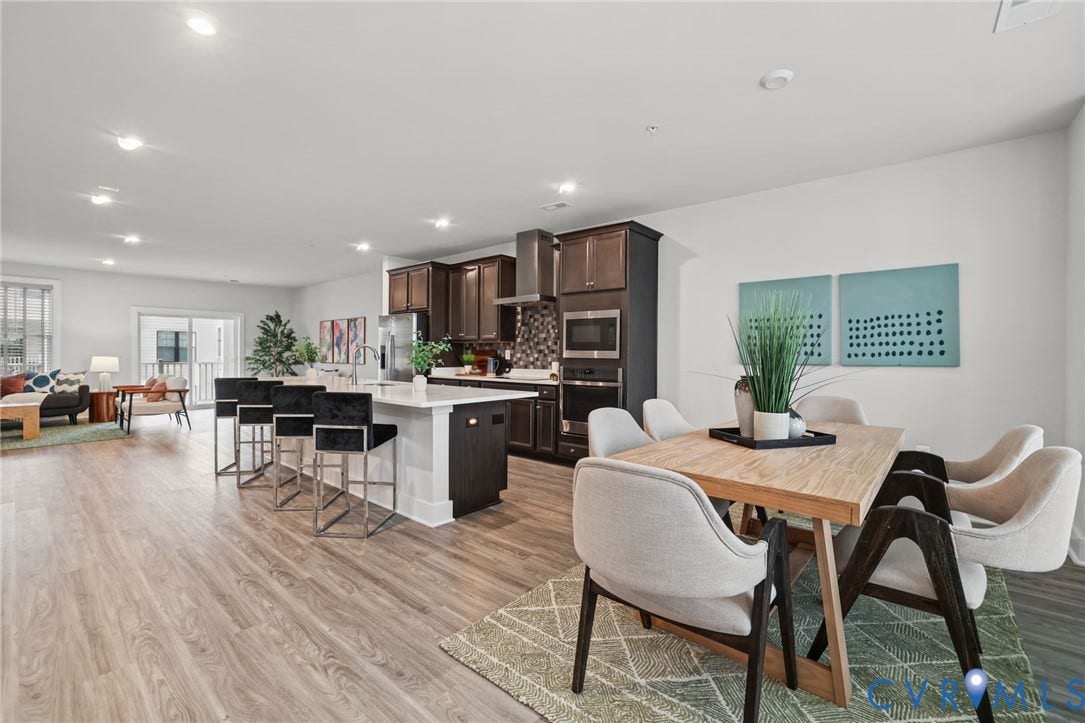 597 Weaver Brook Walk, #B, Richmond, VA 23233 Kitchen featuring dark-finish cabinetry, quartz countertops with a waterfall edge, stainless steel built-in microwave and oven, stone tile backsplash, and wood-finish flooring