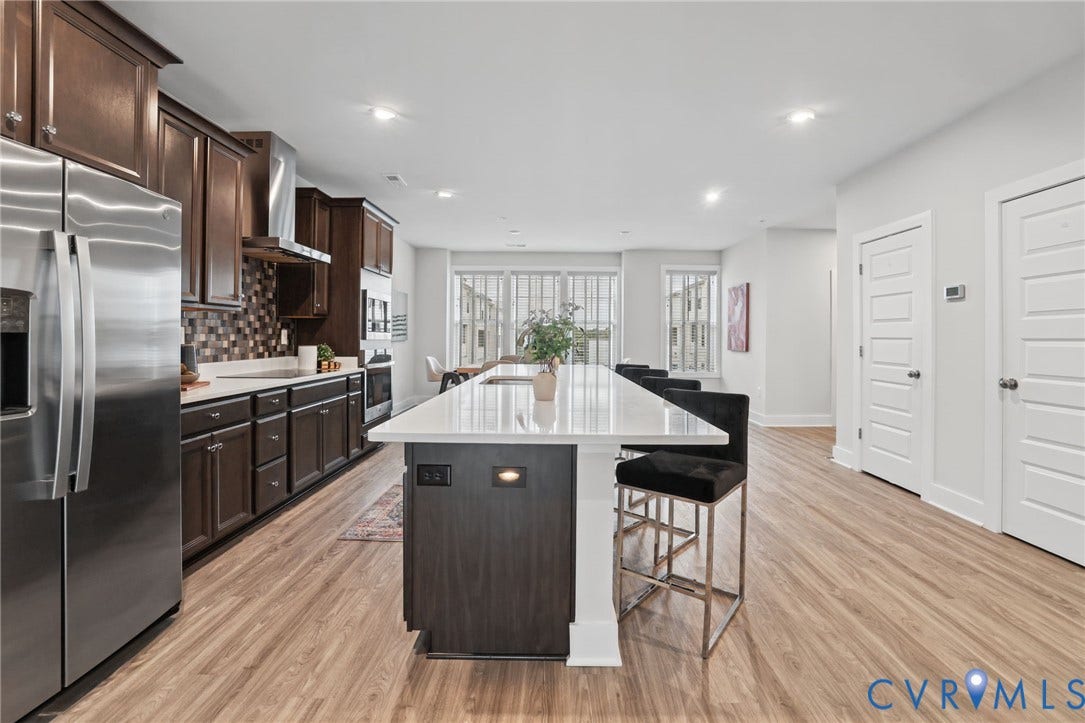 597 Weaver Brook Walk, #B, Richmond, VA 23233 Kitchen featuring an expansive center island with a quartz countertop, dark wood-finish cabinetry, stainless steel appliances, and wood-finish flooring