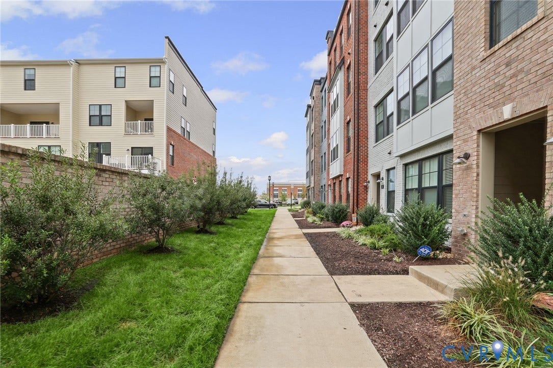 597 Weaver Brook Walk, #B, Richmond, VA 23233 Exterior facade featuring a combination of brick and siding, concrete walkway, manicured lawn, and landscape shrubbery