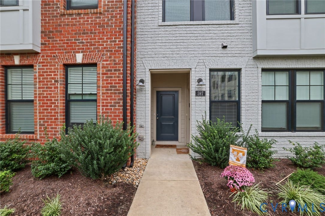 597 Weaver Brook Walk, #B, Richmond, VA 23233 Exterior facade featuring red and white brick masonry, a concrete walkway, multi-pane windows with dark frames, and an entry door with a multi-panel design
