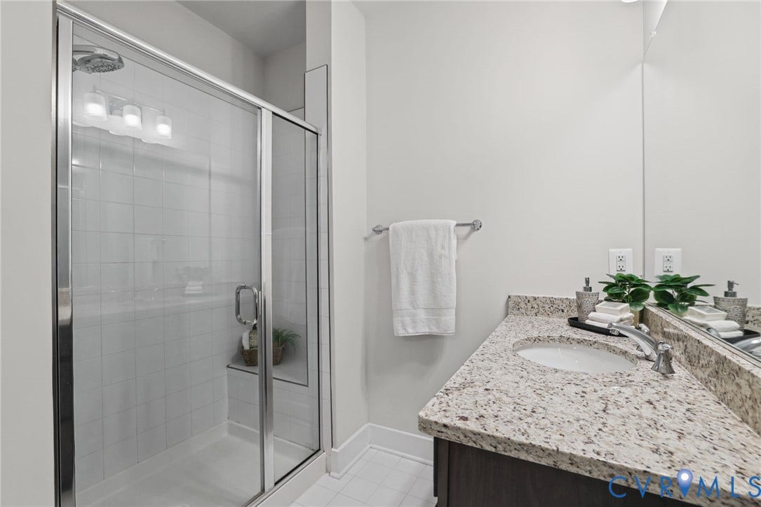 597 Weaver Brook Walk, #B, Richmond, VA 23233 Bathroom featuring a shower with a glass enclosure and built-in bench, stone-composite countertop, undermount sink, and full-width vanity mirror
