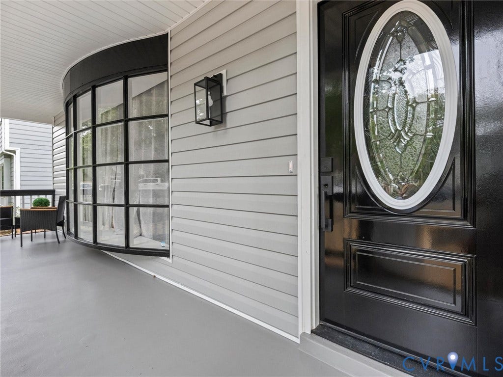 2031 Esquire Road, Midlothian, VA 23235 Light gray siding exterior with a curved bay window, black grid-pattern window frames, and a black front door with an oval leaded glass insert