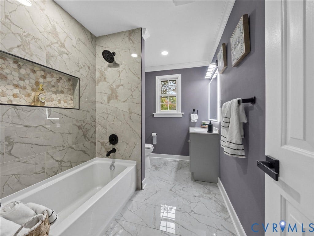 2031 Esquire Road, Midlothian, VA 23235 White soaking tub with a tiled surround, recessed shower niche with pebble-tile accent, and matte black fixtures