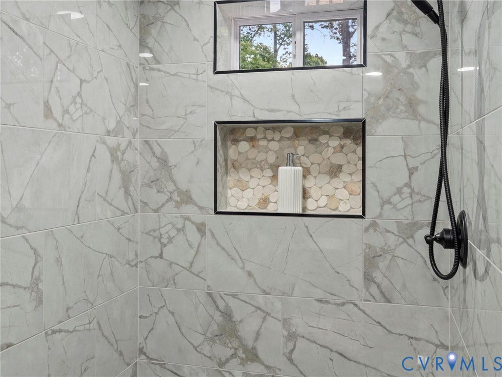 2031 Esquire Road, Midlothian, VA 23235 Shower enclosure with large format stone-look tile, matte black shower fixtures, and a recessed niche featuring pebble tile