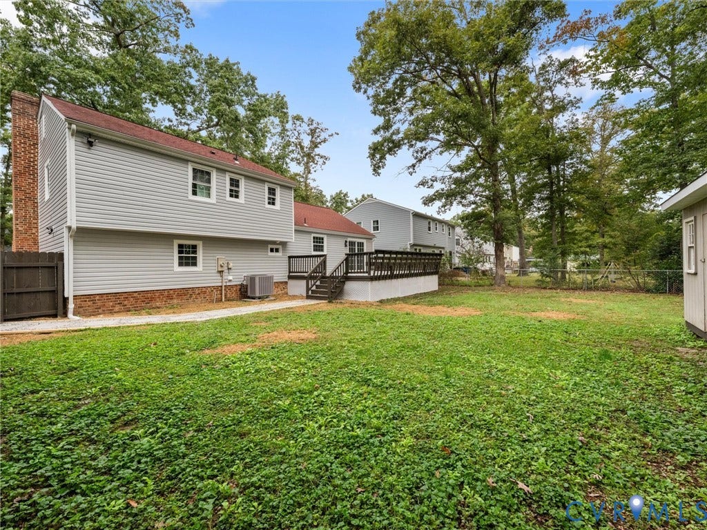 2031 Esquire Road, Midlothian, VA 23235 Expansive backyard featuring a lush lawn, mature trees, and a sizable wooden deck