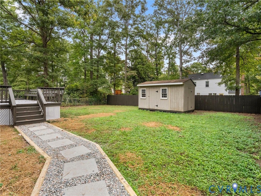 2031 Esquire Road, Midlothian, VA 23235 Expansive backyard featuring a wood deck with stairs, a gravel and paver pathway, a storage shed, and a privacy fence