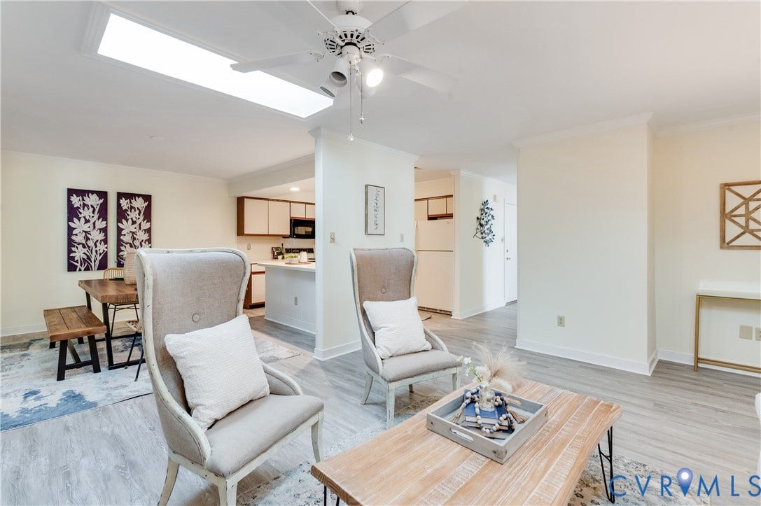 Recessed skylight, ceiling fan, wood-finish flooring, crown molding, and kitchen with wood cabinetry