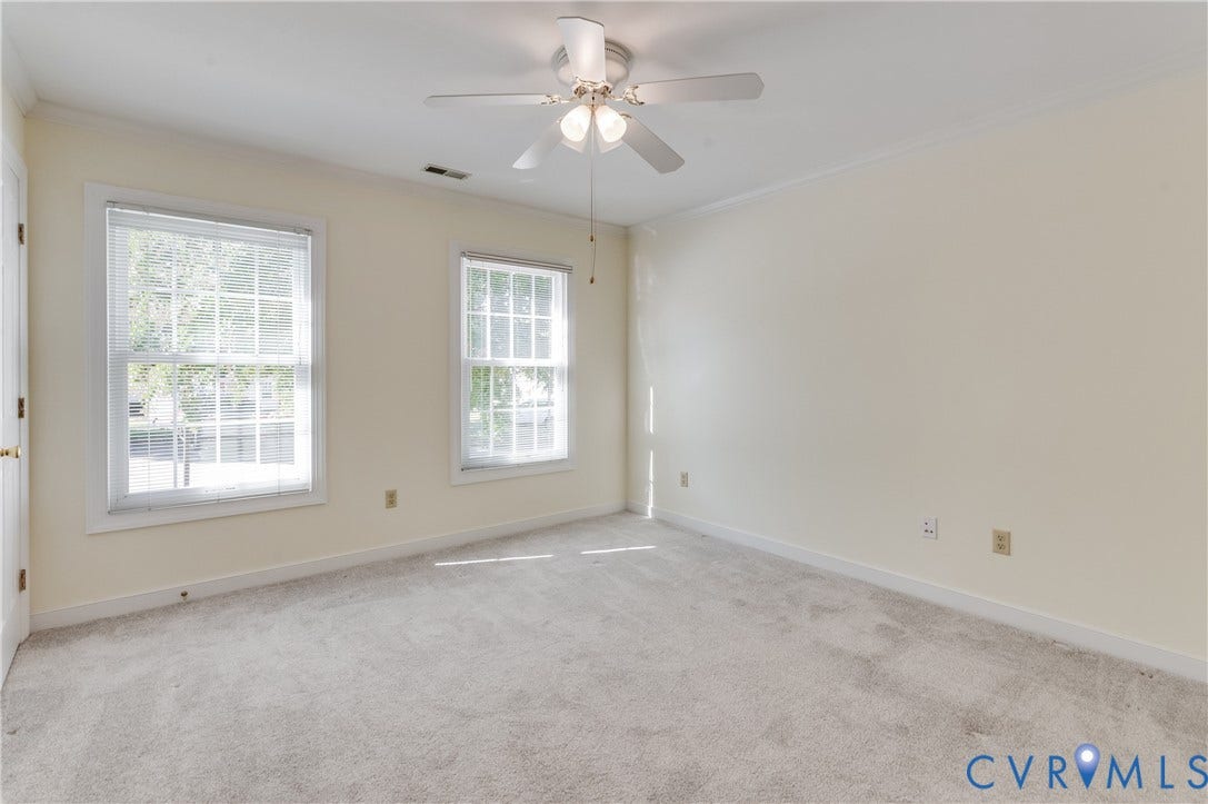 Soft carpet flooring, two double-hung windows, and a ceiling fan with integrated lighting