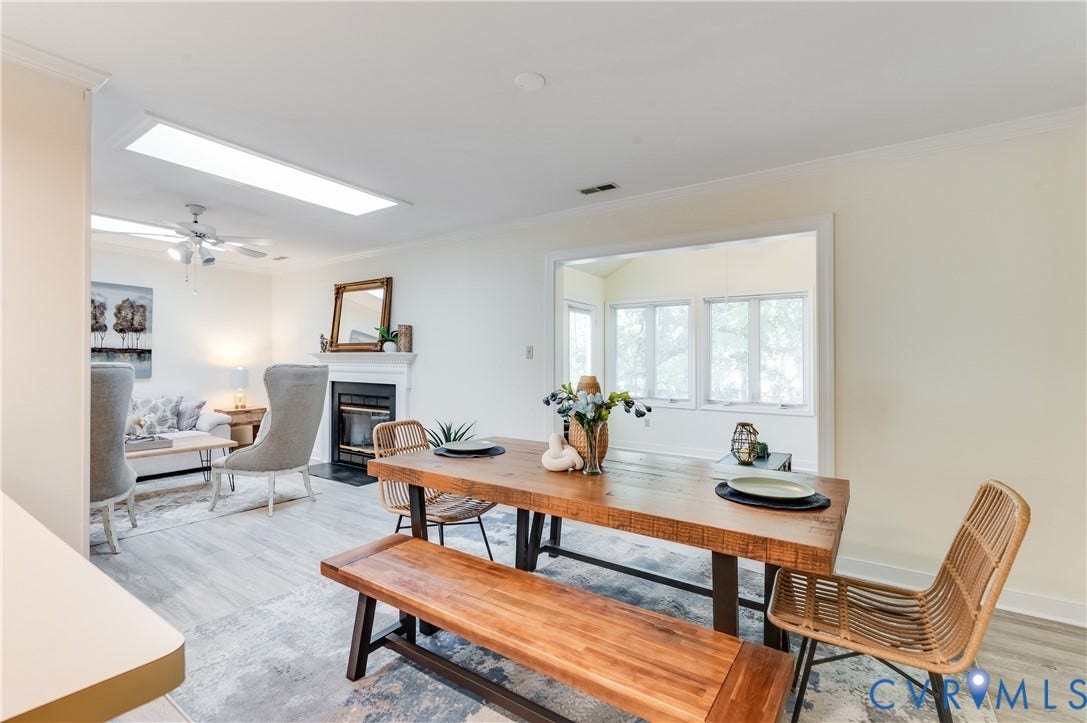 Dining area featuring wood-finish flooring, a wood dining table, and a built-in fireplace in the adjacent living area