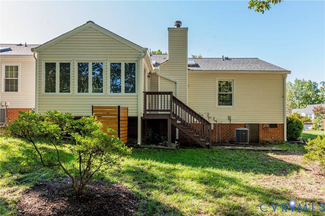 Rear exterior with vinyl siding, a sunroom featuring multiple windows, and a raised wooden deck with stairs