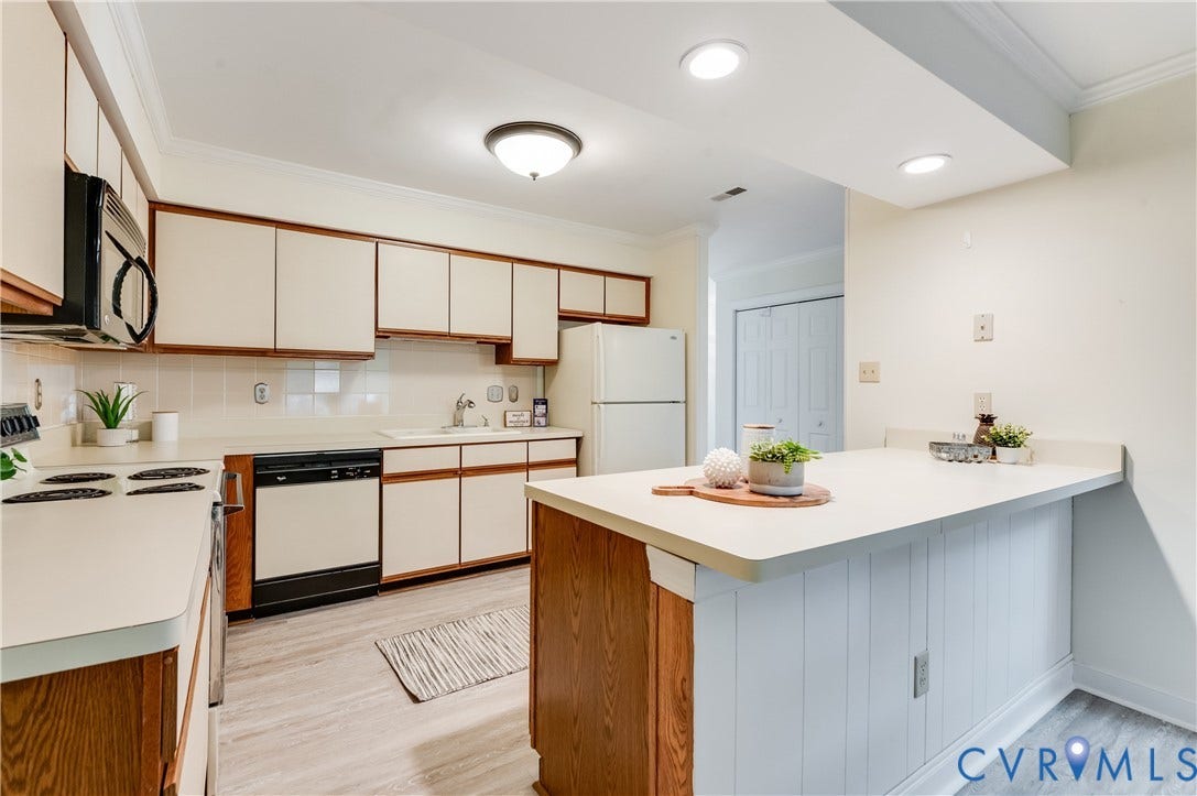 Kitchen featuring wood-finish flooring, white cabinetry with wood trim, white countertops, and a built-in breakfast bar