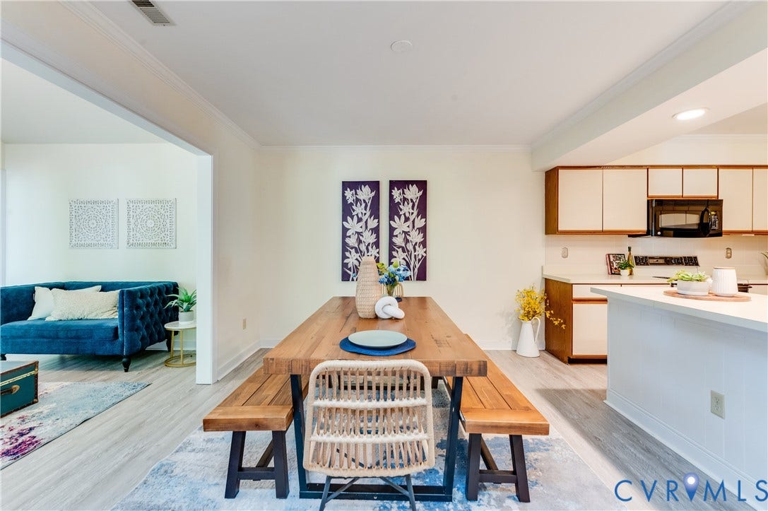 Open concept dining area featuring wood-finish flooring, recessed lighting, and a kitchen with white cabinetry and dark appliances