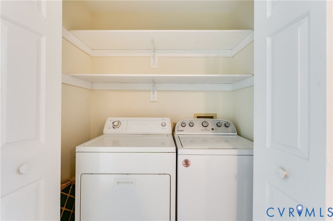 Laundry closet featuring a built-in washer and dryer, and two white storage shelves