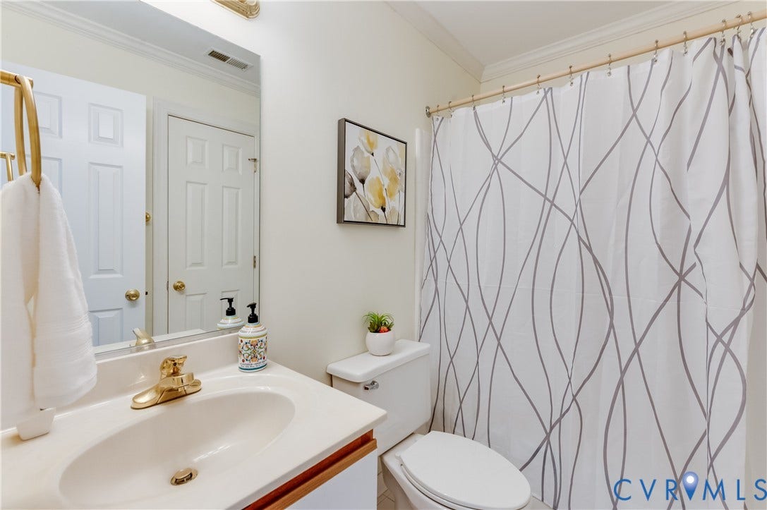White vanity with an integrated sink and gold-tone faucet, complemented by a large wall-mounted mirror