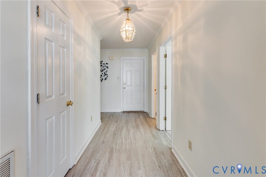 Light-toned wood-finish flooring extending throughout, crisp white walls, and a decorative ceiling light fixture
