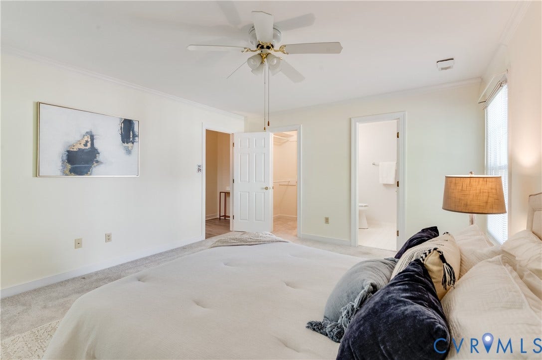 White walls with crown molding, ceiling fan, carpet flooring, and two interior doorways