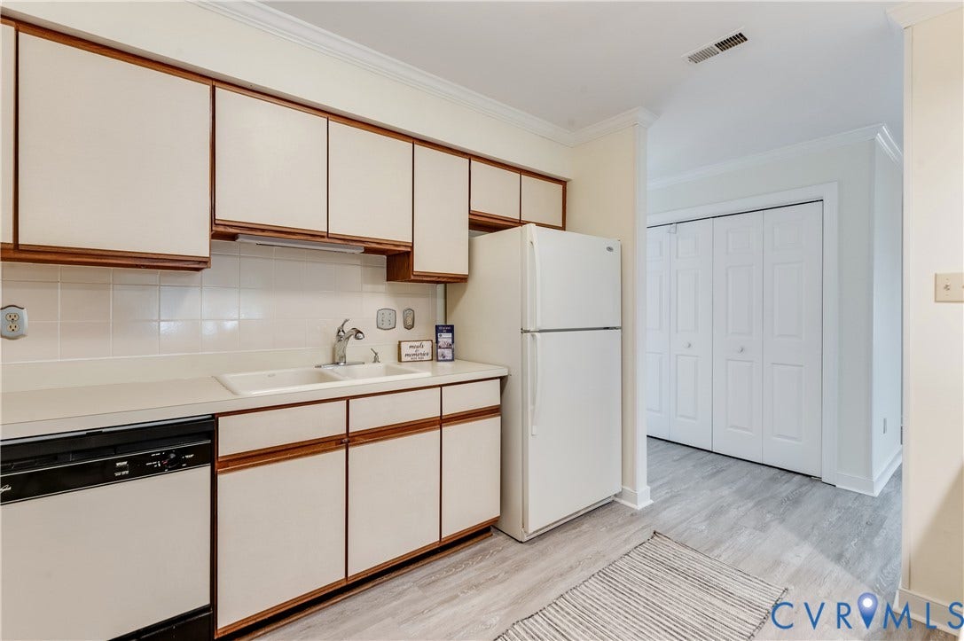 Kitchen with wood-detailed cabinetry, solid surface countertops, and white tile backsplash