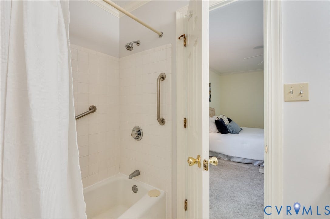 Bathtub with white tile surround and grab bars