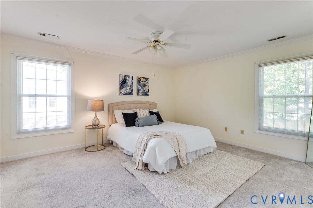 Bright room featuring dual windows, crown molding, and a ceiling fan