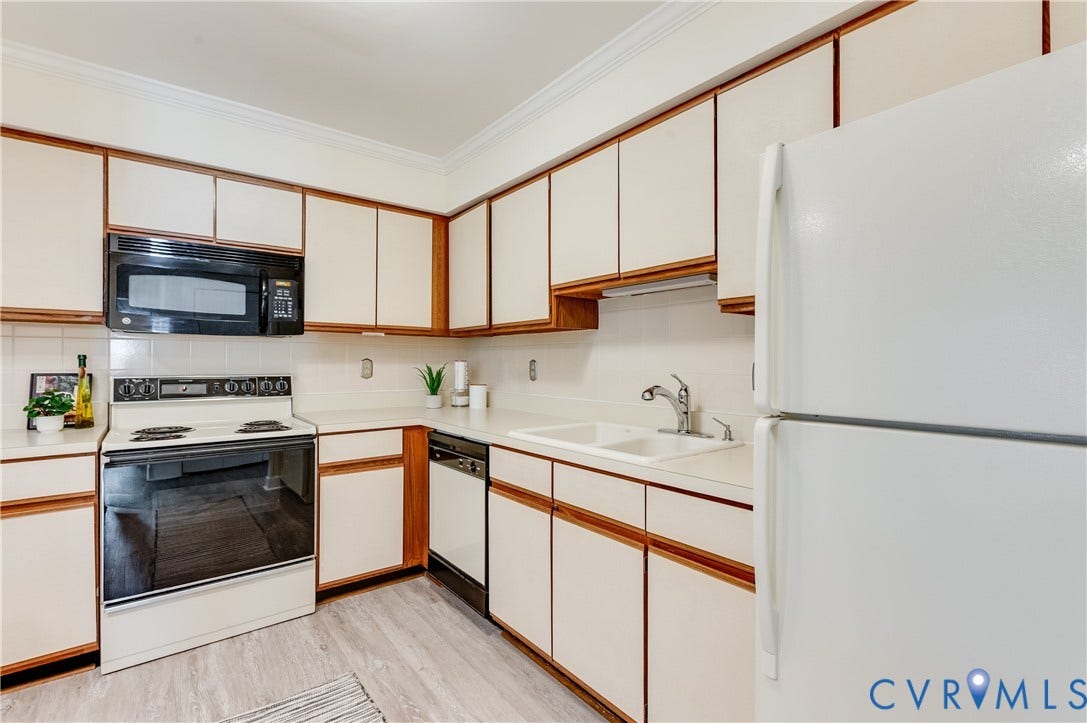 Kitchen featuring wood-finish cabinetry with white panel inserts, white countertops, and a white tile backsplash